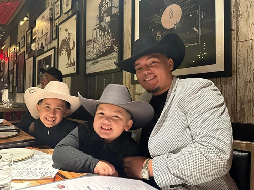 Jose Ortiz with his two sons, all wearing cowboy hats and smiling